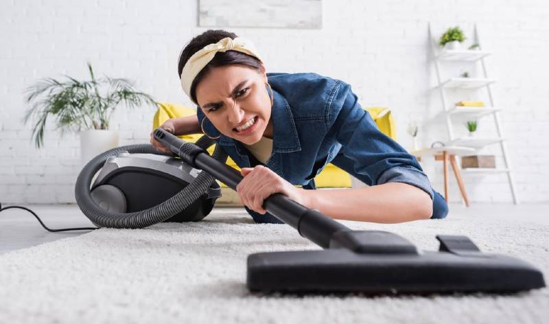 Woman vacuuming carpet inside a room