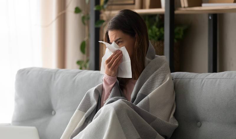 Woman on safe covering with blanket holding her nose with white paper