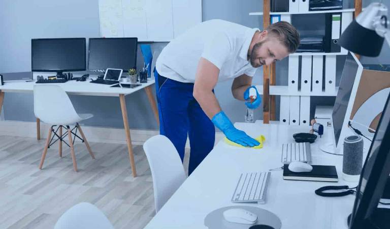 Man in white t-shirt and blue jeans scrubbing furniture in a office