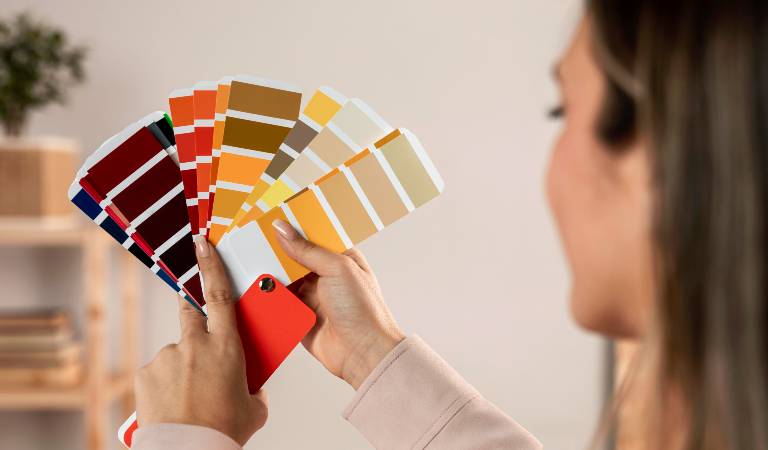Woman holding a red mobile in her left and and different color samples in right hand
