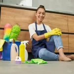 young woman smiling at camera while resting after cleaning floor