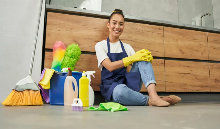 young woman smiling at camera while resting after cleaning floor