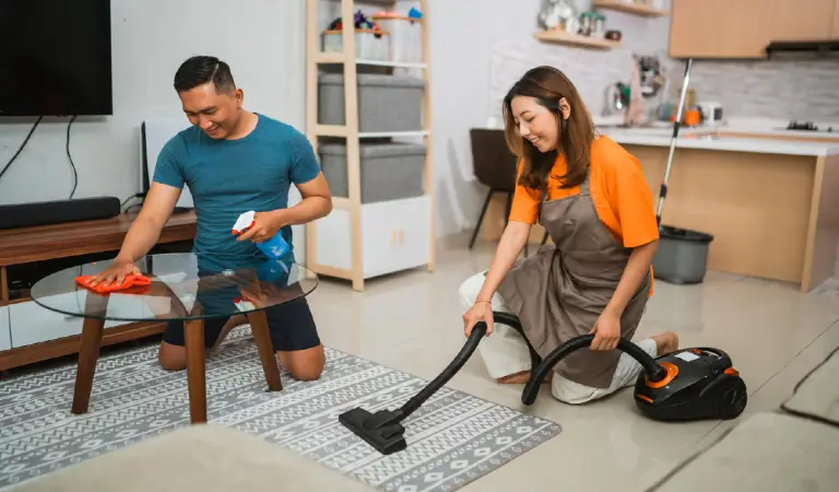 Happy asian couple cleaning their living room together