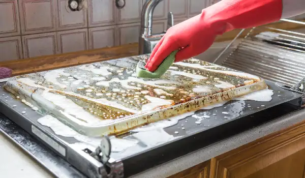Cleaning the oven man's hand in household cleaning gloves cleans oven inside