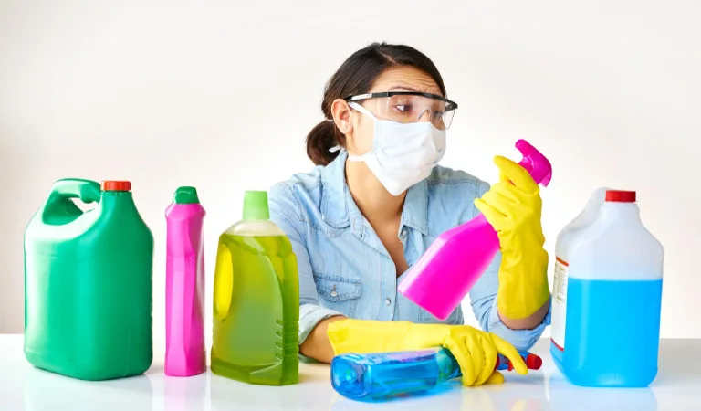 Detergent bottles gloves and woman with mask or glasses for protection safety and cleaning at home housekeeping cleaner