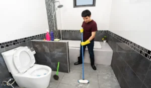 Young man using brush to cleaning the tile in the bathroom