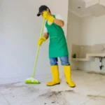 Male janitor clean floor with broom in dirty house